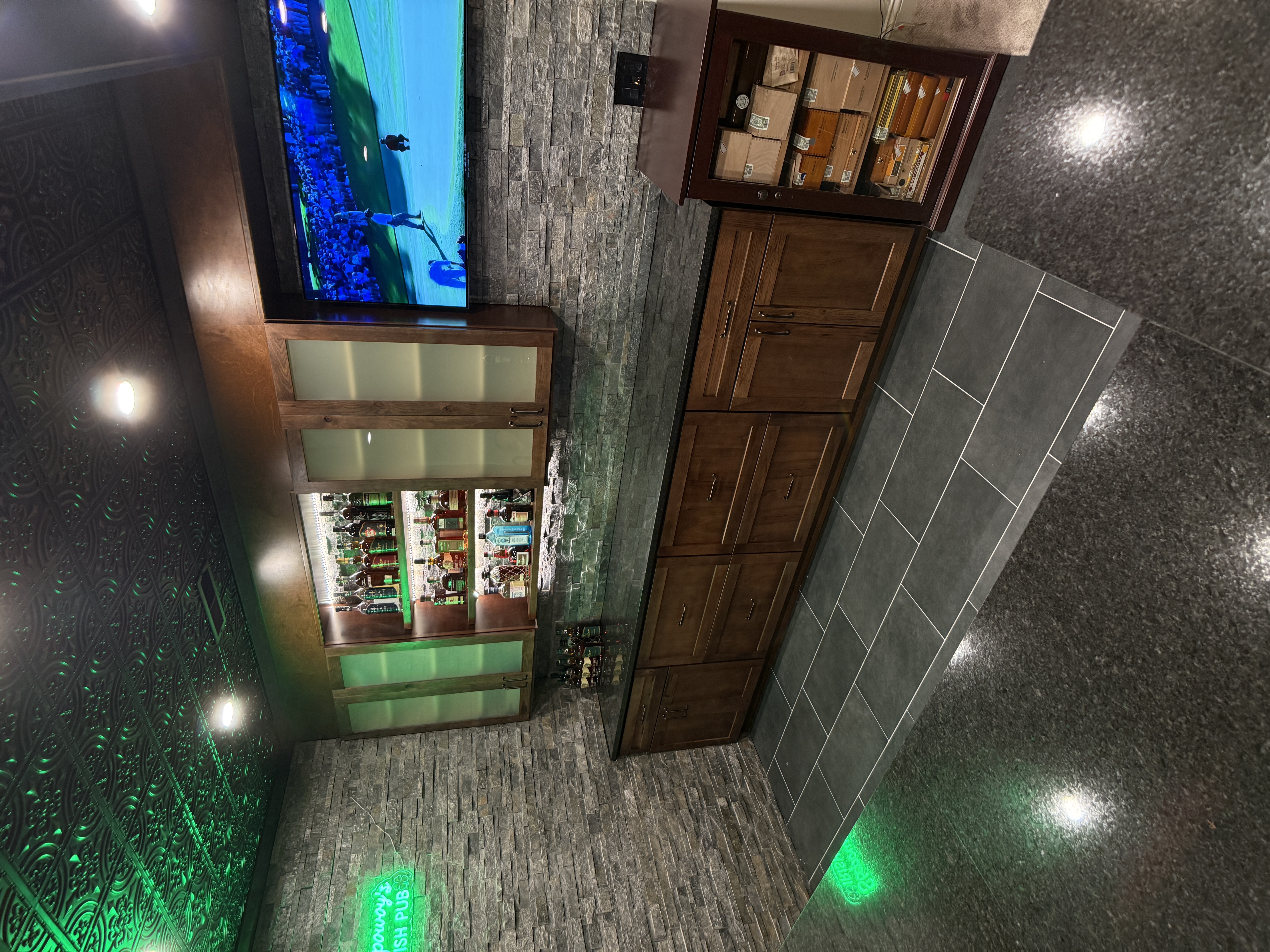 Basement bar with stacked stone walls, mounted TV and cigar humidor by Serge Construction