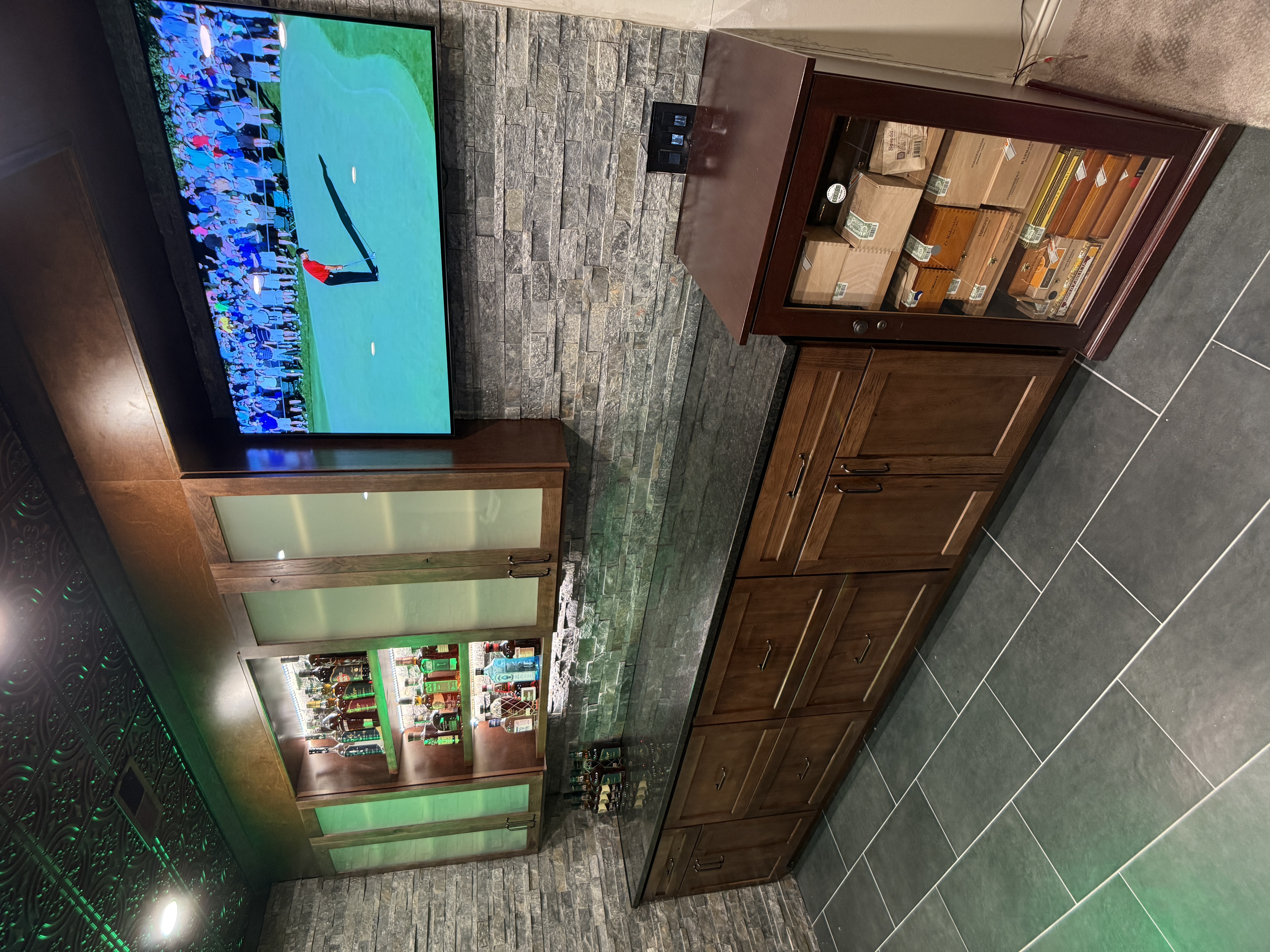 Basement entertainment bar with mounted TV and cigar cabinet by Serge Construction
