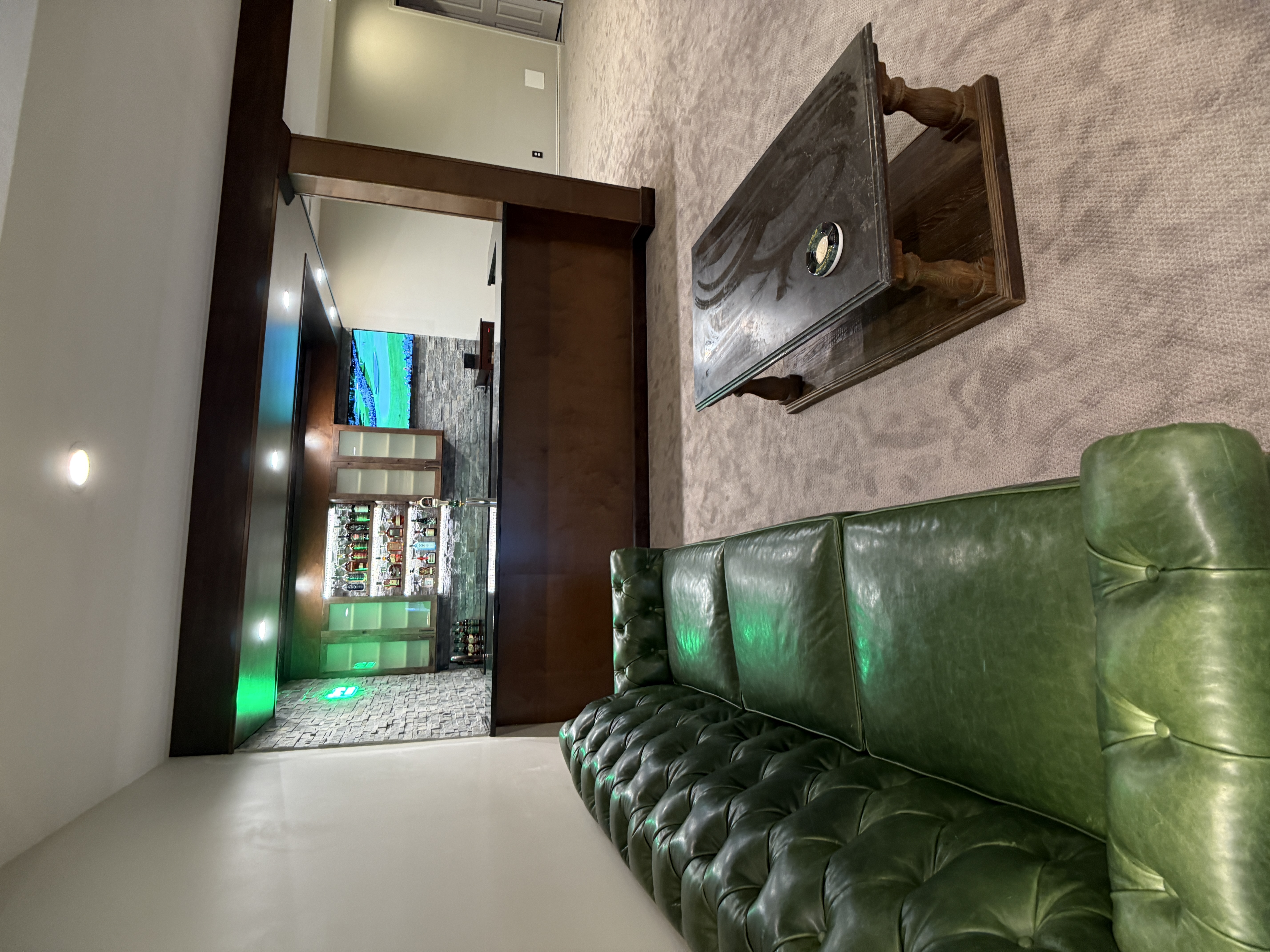 Finished basement lounge with green leather seating and custom wet bar by Serge Construction