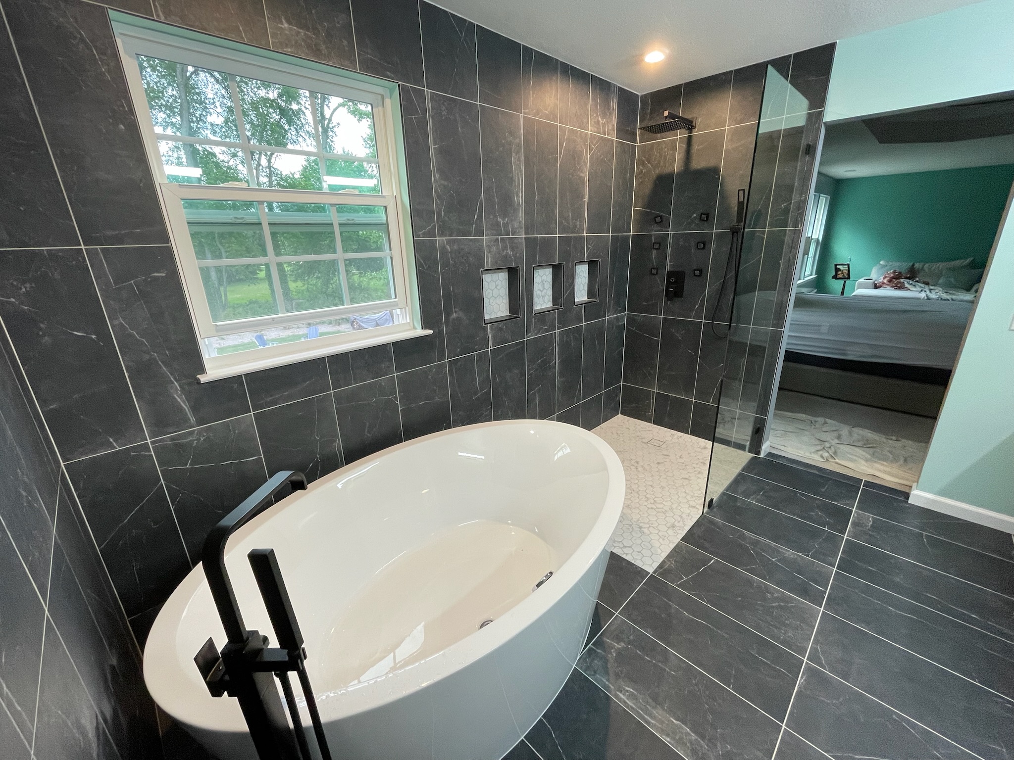Master bathroom with freestanding tub and black marble tile walk-in shower by Serge Construction