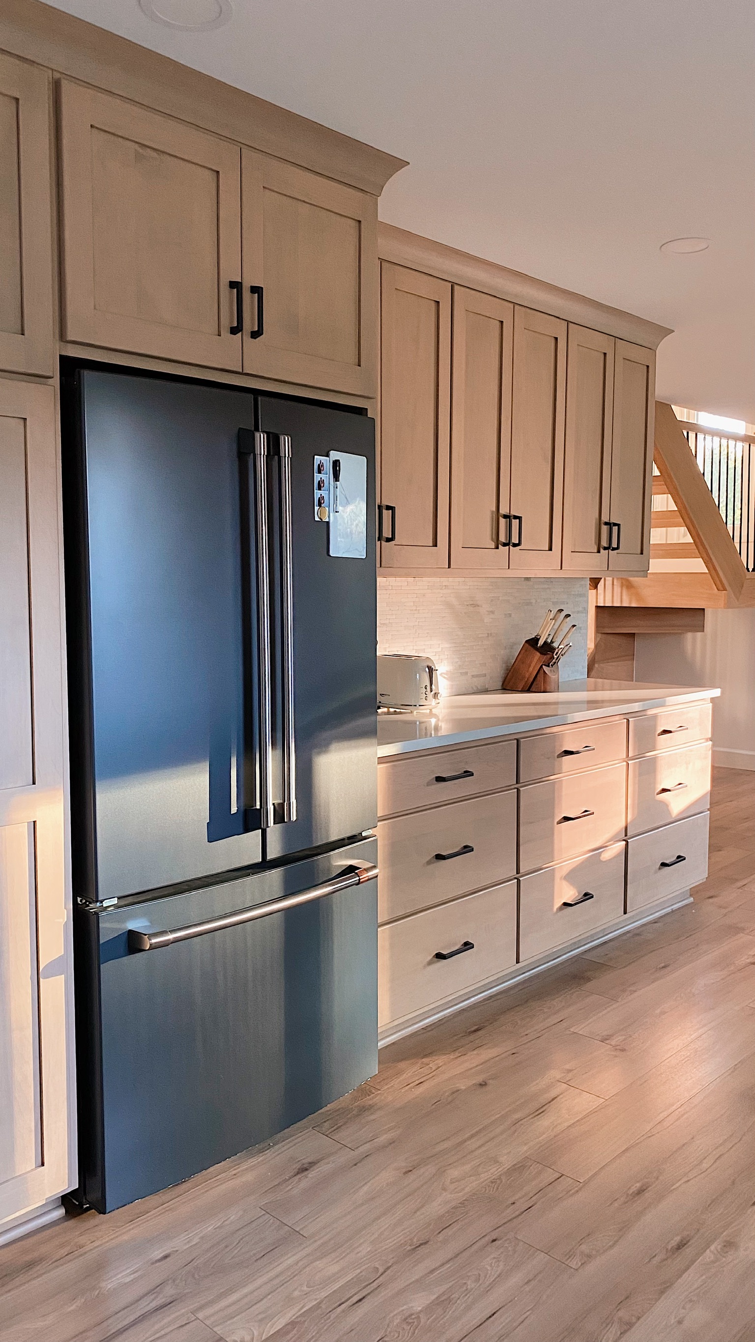 Kitchen remodel with natural wood cabinets and stainless refrigerator by Serge Construction