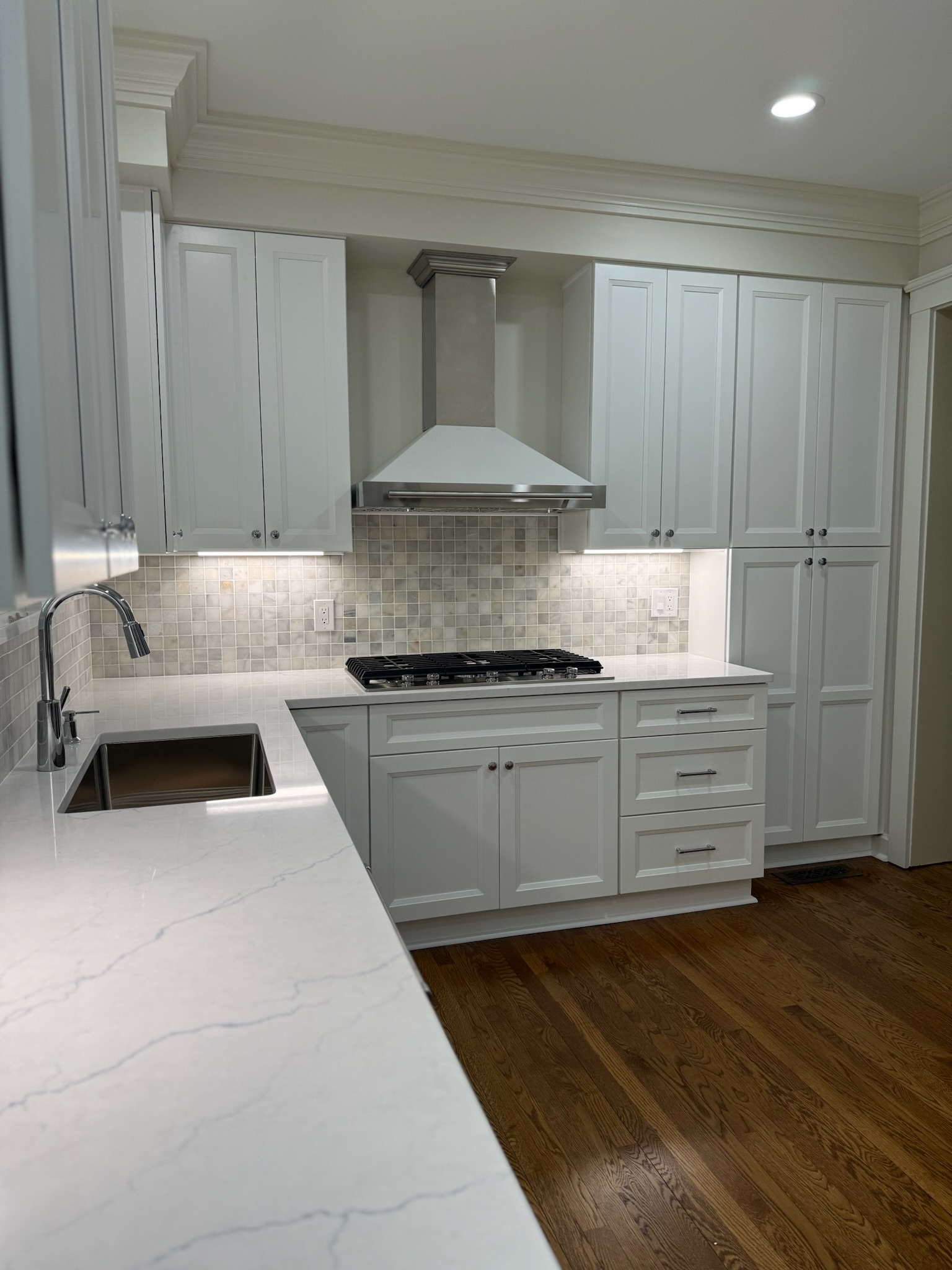 White kitchen remodel with island, range hood and gas cooktop by Serge Construction